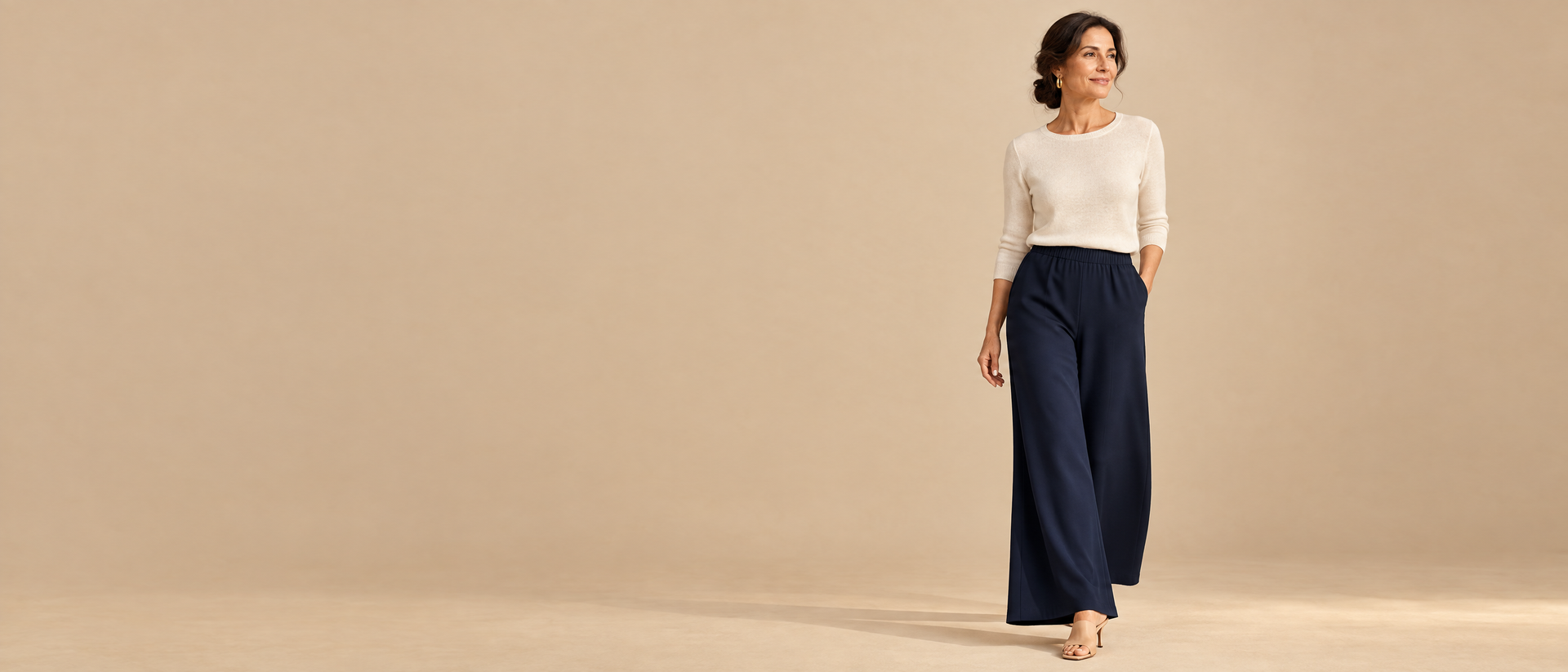 Look Dorabella con maglia color panna e pantaloni palazzo blu.